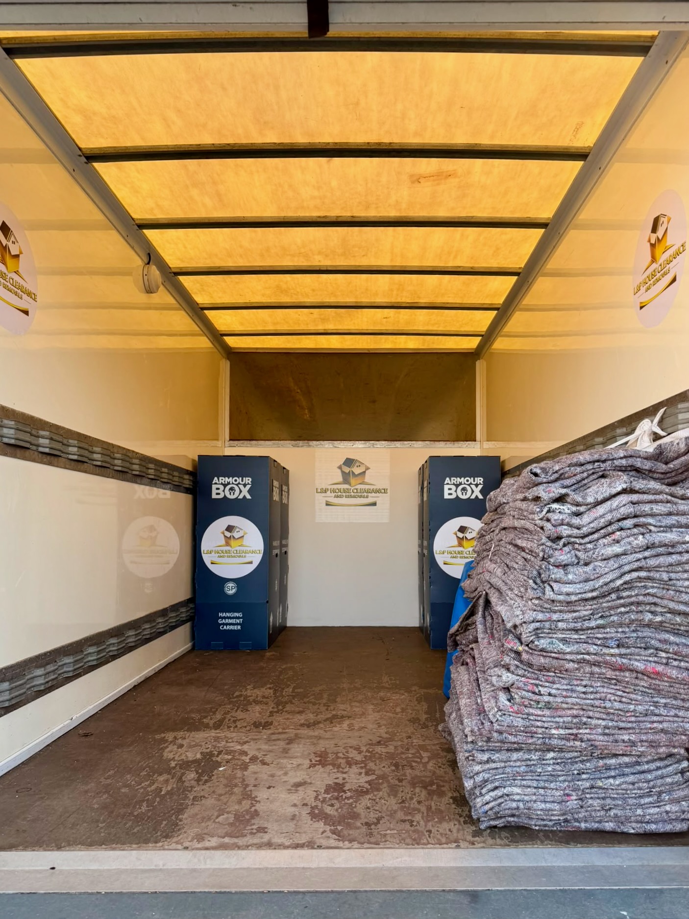 Inside the L&P removals van loaded with wardrobe boxes and packing blankets